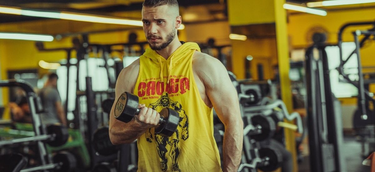 a man in a gym holding a pair of dumbs