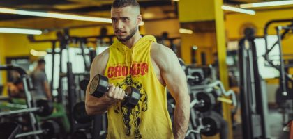 a man in a gym holding a pair of dumbs