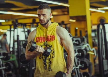 a man in a gym holding a pair of dumbs